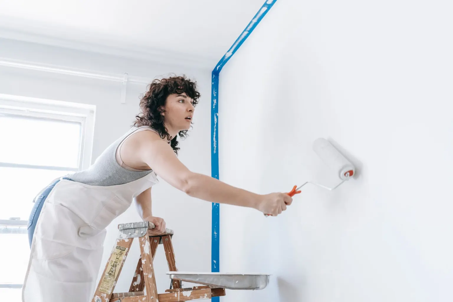 Decorator painting an interior wall with a roller