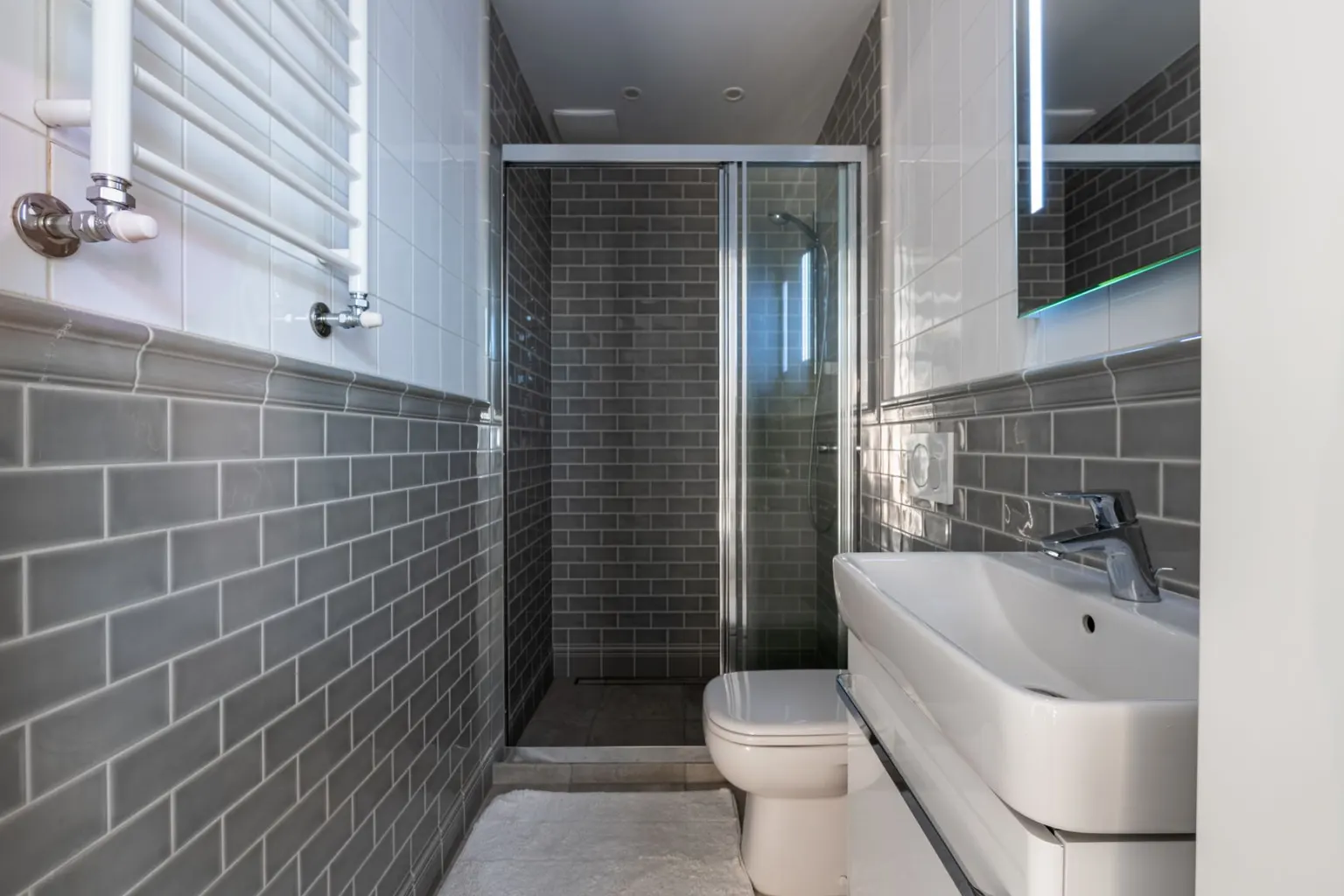 Grey tiled bathroom with a walk-in shower and vanity unit